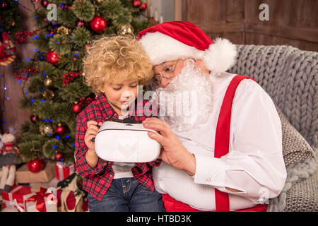 Santa Claus sitting with child and using virtual reality headset Stock Photo