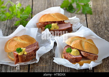 Bavarian takeaway food: Three rolls with baked meat loaf and mustard on wrapping paper with a napkin