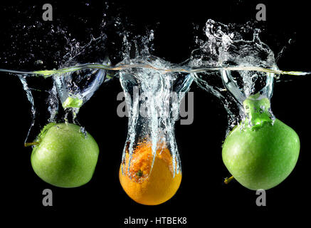 Splash water with droping oranges and apples in art mixed in studio technical speed and lighting. Stock Photo