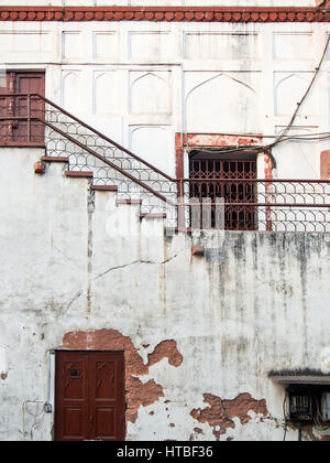 An old building with white cracked plaster and rusty doors and railings in Delhi, India. Stock Photo