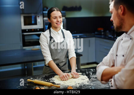 Happy girl talking to chef during work in the kitchen Stock Photo