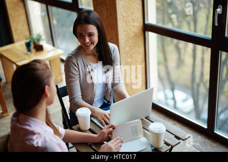 Two friendly girls discussing and carrying out task Stock Photo