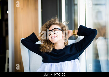 Business woman relaxing working at office desk laid back resting on chair with hands behind head . Stock Photo