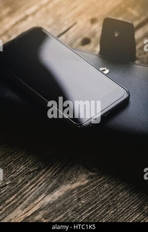 Black smartphone with wallet on wooden background. Stock Photo