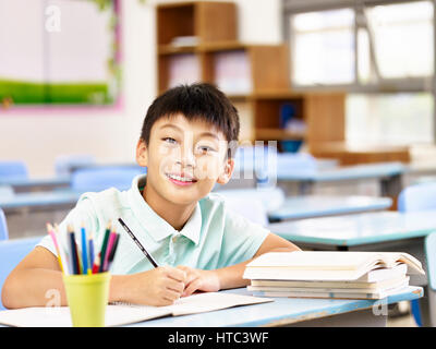 happy asian elementary school boy studying in classroom, looking at camera smiling. Stock Photo