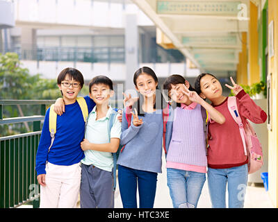 group of happy smiling primary school student posing on corridor of classroom building. Stock Photo