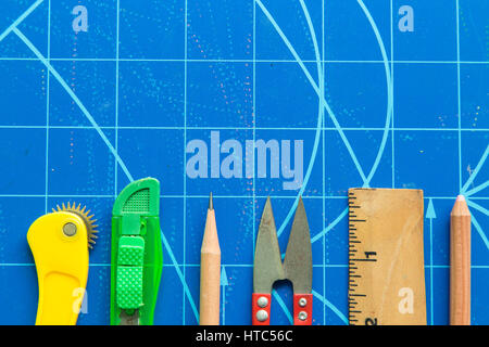 Closeup of ruler,scissors, cutter, pencil on blue cutting mat. Stock Photo