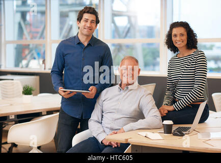 Portrait of a casually dressed diverse team of smiling business professionals working together at a table in a modern office Stock Photo
