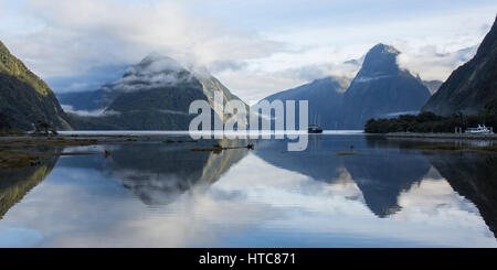 Milford Sound, Fiordland National Park, Southland, New Zealand. Panoramic view down Milford Sound, mountain peaks reflected in still water. Stock Photo