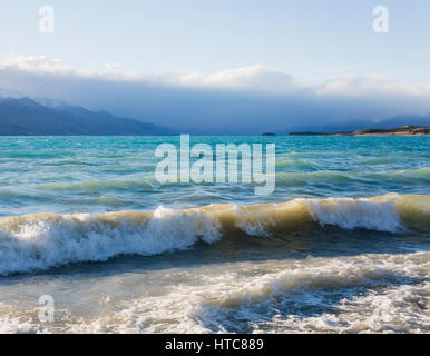 Twizel, Canterbury, New Zealand. View from shore across the stormy turquoise waters of Lake Pukaki, the Southern Alps obscured by cloud. Stock Photo