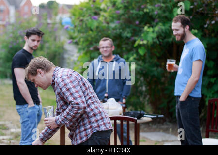 Group of young man friends meeting after work for drinking beer, BBQ in garden backyard in Woking, England. Horizontal composition Stock Photo