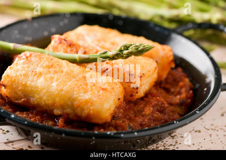 closeup of a frying pan with bacalao a la vizcaina, a typical spanish recipe of codfish, with a tomato sauce with garlic, onion and red pepper Stock Photo