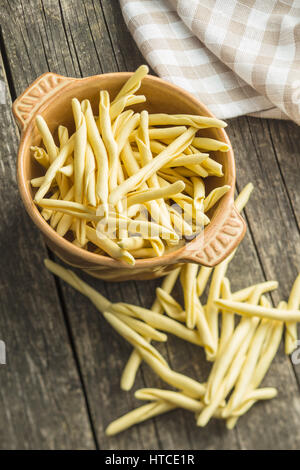 Raw italian pasta in bowl on old wooden table. Stock Photo