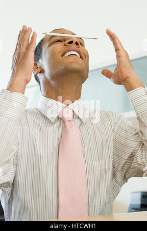 Office worker balancing a pencil on his nose Stock Photo