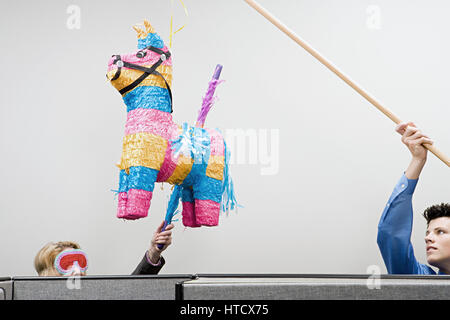 Office workers playing with a piñata Stock Photo