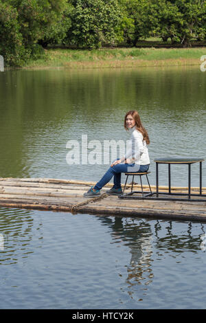 Woman sitting on a bamboo raft in the river Stock Photo