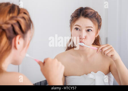 woman cleaning mouth using toothbrush with mirror in the bathroom Stock Photo