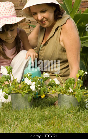 Girl and grandmother watering plants Stock Photo