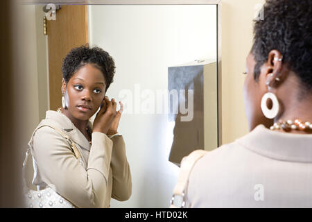 Woman putting on earrings Stock Photo