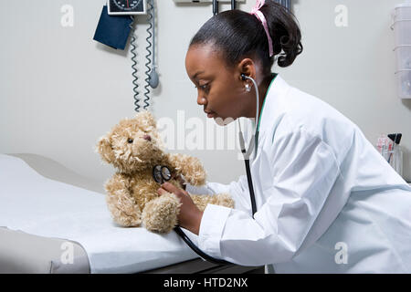 Girl doctor using stethoscope on teddy bear Stock Photo