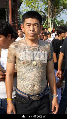 A tattooed devotee attends the “Wai Khru” ceremony at   Wat Bang Phra Temple.  Some go into a trance-like state where they are 'possessed' by the spirit of an animal which is tattooed onto their skin by monks.  What Bang Phra is famous for its magically charged tattoos and amulets, which can protect its wearer against harm and even speeding bullets. Stock Photo