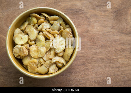 Salted broad beans in bowl on wooden background. Stock Photo
