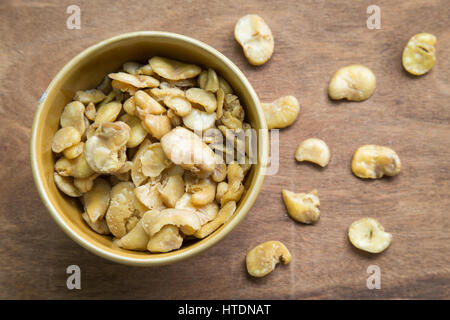 Salted broad beans in bowl on wooden background. Stock Photo