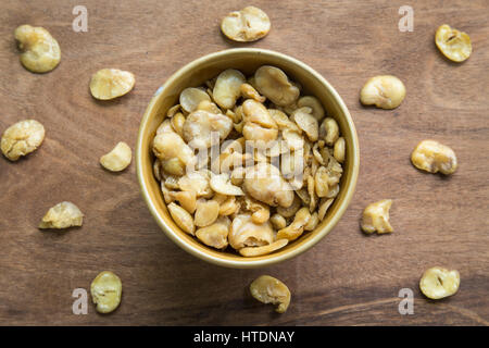 Salted broad beans in bowl on wooden background. Stock Photo