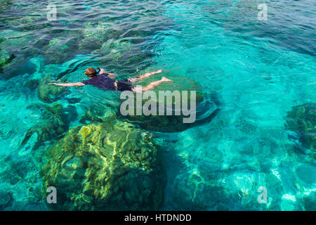 Young man snorkeling over coral reef in transparent tropical sea, Rok island, Thailand. Stock Photo