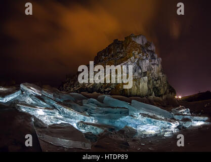 Illuminated hummocks of ice in front of a rock shaman on an olkhon. Stock Photo