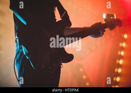 Silhouette of bass guitar player with colorful stage illumination, live rock music theme Stock Photo