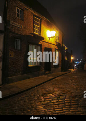 Street Light, wall mounted, Lincoln City, cast iron, cobbles, old gas unit, converted, night time, reflections, remote, low pressure sodium, amber old Stock Photo