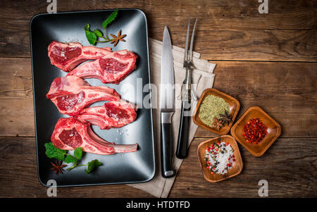 Raw fresh lamb ribs with spices on plate on wooden background, top view Stock Photo
