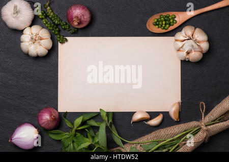 Vegetable recipe. Open menu book with fresh herbs and spices on dark background Stock Photo