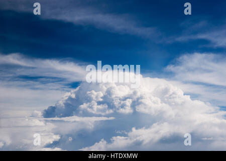 Airplane window seat view of big white thick fluffy clouds with a clear blue sky at the background in the afternoon. Stock Photo