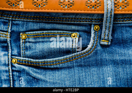 Detail of jeans trousers with brown leather belt close-up. Pockets, pants, belt loops, thick stitches. Elements of denim pants background Stock Photo