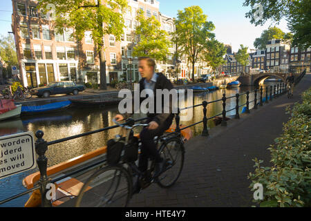 Cycling to work along one of Amsterdam's canal tow paths, on a sunny morning Stock Photo