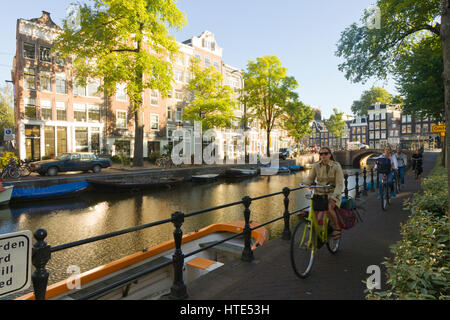 Cycling to work along one of Amsterdam's canal tow paths, on a sunny morning Stock Photo