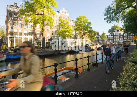 Cycling to work along one of Amsterdam's canal tow paths, on a sunny morning Stock Photo