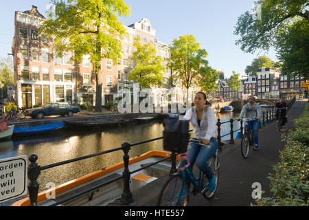 Cycling to work along one of Amsterdam's canal tow paths, on a sunny morning Stock Photo