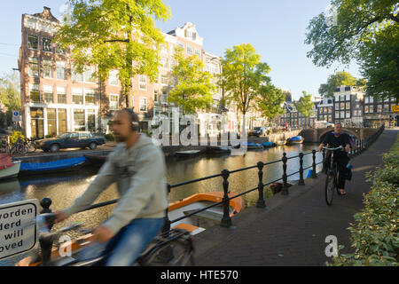 Cycling to work along one of Amsterdam's canal tow paths, on a sunny morning Stock Photo