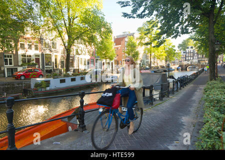 Cycling to work along one of Amsterdam's canal tow paths, on a sunny morning Stock Photo