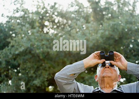 Senior man looking through binoculars Stock Photo