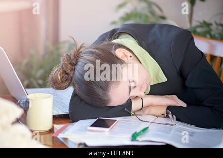Tired and overworked young corporate girl fallen asleep during her work Stock Photo