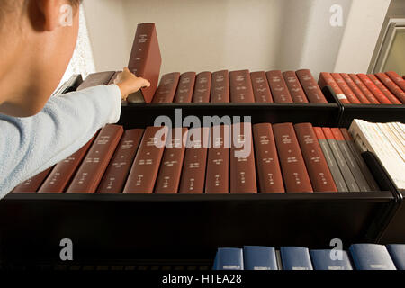 Female student reaching for a book Stock Photo