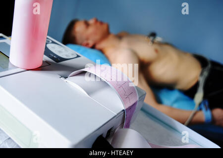 Electrocardiogram, ECG in hand. Clinic of Cardiology heart rate and pulse test closeup. Cardiogram printout on a male patient background Stock Photo