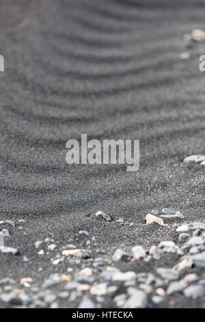 An arid landscape of rocks and by wind created patterns of black volcanic sand in Iceland, Europe. Stock Photo