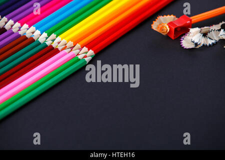 colored pencils on dark background lying in opposite corners and one pencil with sharpener and shavings. Angle. Drawing and painting. Hobbi. Artist. A Stock Photo