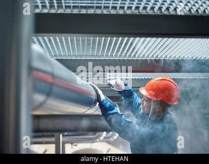 Technician, mechanic with orange helmet mounting a refrigeration line bracket, Austria Stock Photo