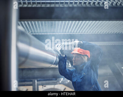 Technician, mechanic with orange helmet mounting a refrigeration line bracket, Austria Stock Photo